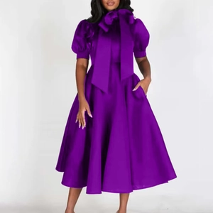 Détail de robe midi violette avec manches bouffantes et nœud géant au décolleté