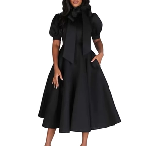 Détail du col montant à nœud et manches bouffantes sur une robe trapèze noire chic
