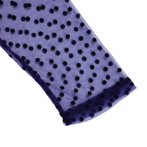 Detailed macro view of purple mesh fabric with black flocked polka dots and hemmed edges