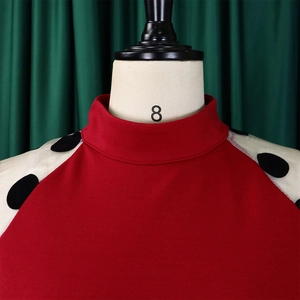 Detail des roten Stehkragenkleids mit kontrastierenden gepunkteten Ärmeln am Mannequin