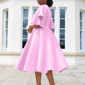 Detail view showing bell sleeves and pleated hem of a pink V-neck dress outdoors