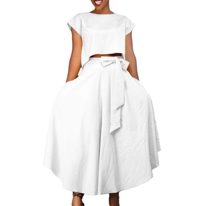 Detail of the high-waisted white maxi skirt with a coordinated bow belt and crop top