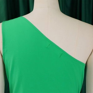 Close-up of shoulder stitching on a bright green one-shoulder dress on a mannequin
