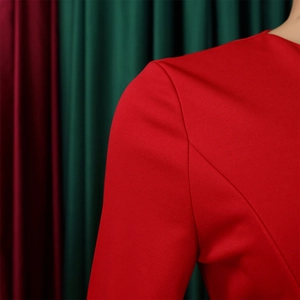 Detail shot of a red long-sleeved dress showing high-quality stitching and fabric texture