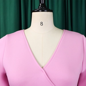 Detail of pink V-neck flared sleeve dress with smooth fabric texture on a mannequin