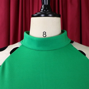 Detail eines grünen Stehkragenkleids mit beigen und schwarzen Polka-Dot-Netzärmeln