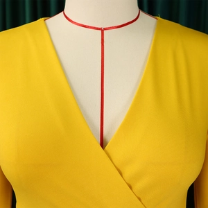 Detail of yellow V-neck dress showing textured woven fabric and overlapping collar craftsmanship