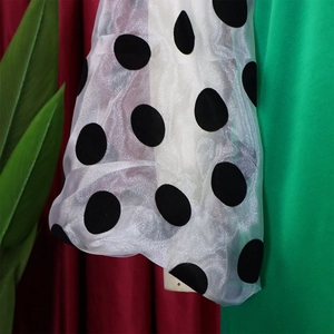 Detail eines weißen Organza-Ärmels mit großen schwarzen Punkten und Mesh-Textur