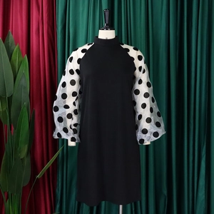 Detail eines schwarzen Kleides mit weißen Mesh-Puffärmeln und großen schwarzen Punkten