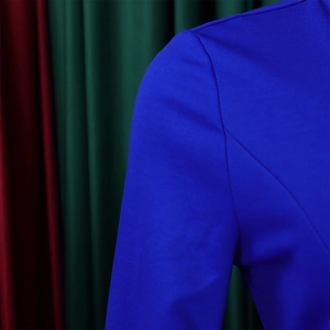 Detailed view of the bright blue dress shoulder seam and smooth knit fabric texture