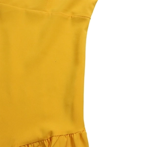 Dettaglio dell'abito giallo a pieghe con orlo a balze, cuciture e texture del tessuto