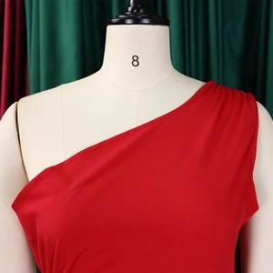 Detail of red one-shoulder dress showing pleated shoulder and diagonal neckline on mannequin