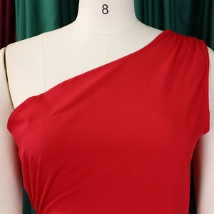 Detail view of the red one-shoulder dress showing textured fabric and side pleats