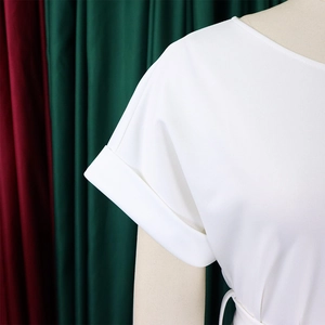 Détail du haut blanc avec lien à la taille, revers aux manches et texture de tissu lisse