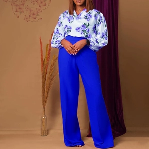 Détail de la blouse en mousseline fleurie et du pantalon large bleu cobalt en ensemble chic