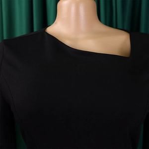 Detailed view of black dress featuring unique asymmetrical neckline and knitted fabric