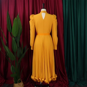 Detail view of the pleated back with drop-shaped cutout and puff sleeves on yellow dress