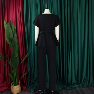 Vue arrière d'un ensemble deux pièces noir élégant avec haut à basque et pantalon long