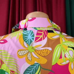 Detail of tropical floral print on pink fabric and collar stitching of the long sleeve shirt