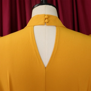 Detail of high-neck yellow top with back keyhole cutout and covered button closures