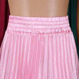 Détail de jupe longue plissée rose en satin avec taille haute élastique et plis fins