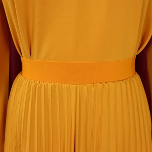 Detailed close-up of the high elastic waistband and pleated texture of the yellow skirt