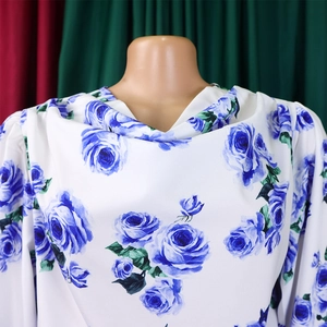 Détail du haut floral blanc élégant avec roses bleues et col roulé plissé chic
