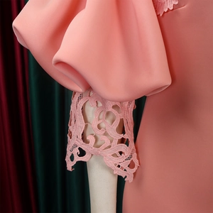 Close-up of coral pink lantern sleeves with intricate hollow-out lace embroidery details