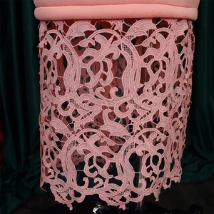Detail shot of pink lace hem with intricate floral patterns on an elegant evening gown