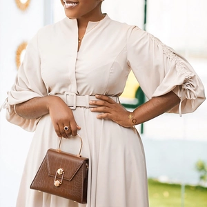 Détails d'une élégante robe beige à manches bouffantes et sac à main façon croco