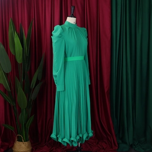 Detailed view of emerald green pleated dress with puff sleeves and cinched waist belt