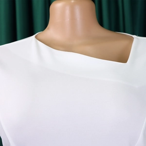 Detailed view of the asymmetric geometric neckline on a white professional dress