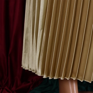 Détail de la jupe plissée en satin doré champagne avec une finition brillante et lisse