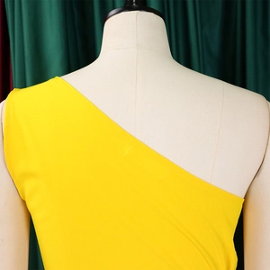 Detail of a bright yellow one-shoulder dress with clean tailoring on a mannequin