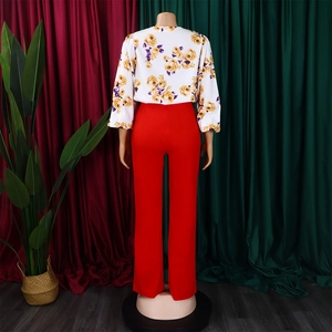 Détail arrière du chemisier à fleurs blanches et du pantalon rouge à jambes larges