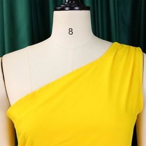Detail of a bright yellow one-shoulder dress with elegant pleated fabric on a mannequin