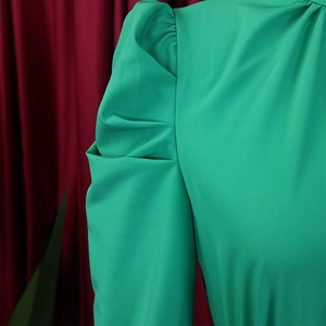 Detail of emerald green puffed sleeves with pleated texture and silky fabric finish