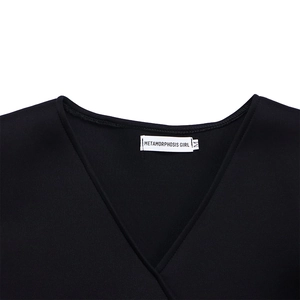 Detail view of the V-neckline and white brand label on a black flared sleeve dress