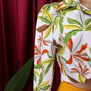 Close-up of tropical leaf print on white long sleeve shirt with sharp collar detail