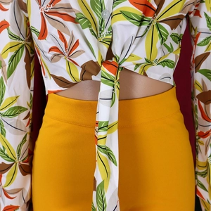 Detail of tropical print tie-front shirt with bright yellow high waist trousers