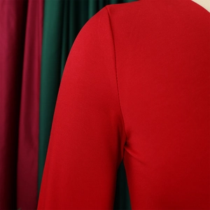 Detailed close-up of shoulder stitching and fine knitted texture on red V-neck dress