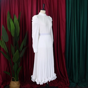 Close-up of white pleated dress with puff sleeves and ruffled hem on a mannequin
