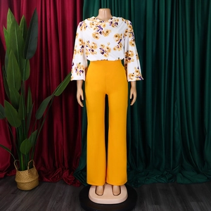 Détail du haut à fleurs et du pantalon large jaune sur un mannequin de présentation