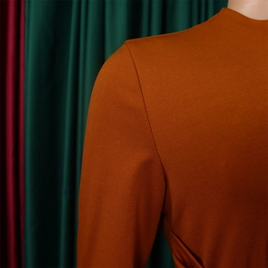 Detailed close-up of the caramel-colored knitted fabric texture and shoulder seam stitching
