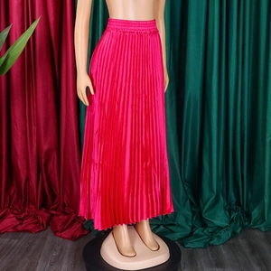 Détail d'une jupe longue plissée fuchsia à taille haute avec texture satinée brillante