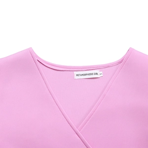 Detail of pink flare-sleeve dress showing V-neckline and inner woven brand label