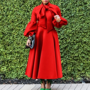 Detail of red lantern sleeve dress featuring oversized bow tie and flared hemline