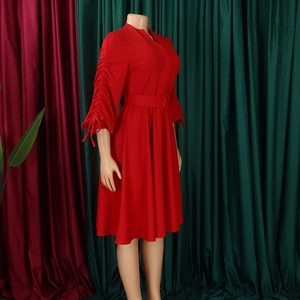 Détail d'une robe rouge col en V avec poignets plissés, nœuds et ceinture en tissu assortie