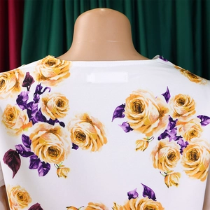 Détail du col rond avec imprimé de roses jaunes et feuilles violettes sur tissu texturé