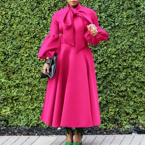 Detail of magenta dress featuring large neck bow, lantern sleeves, and a full skirt